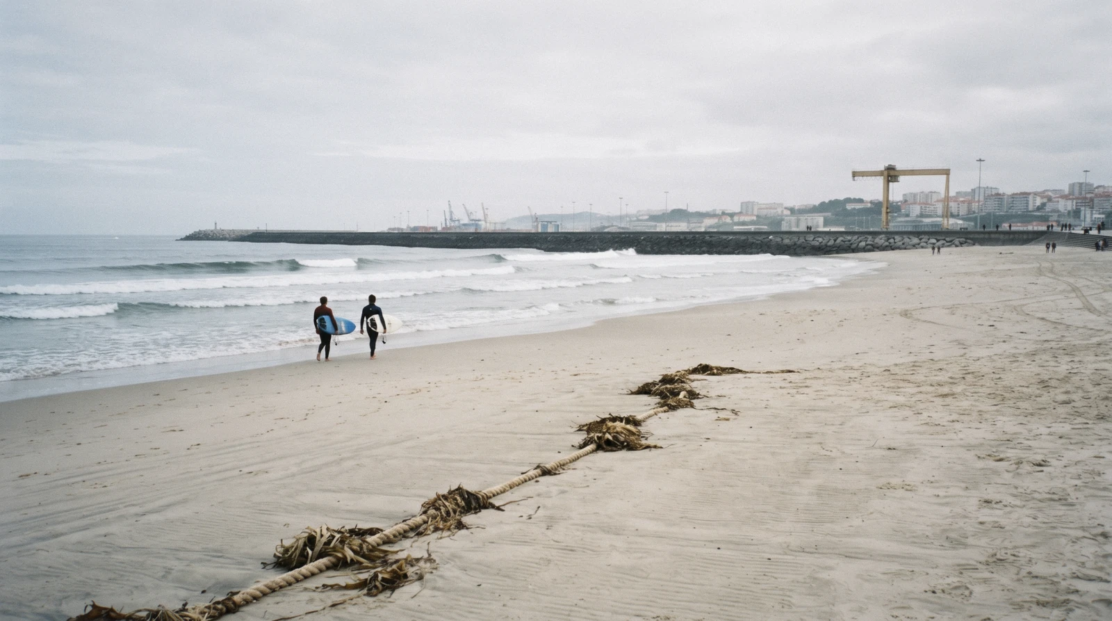 The wide sand at Matosinhos at half past nine on a September morning with the harbour wall to the north and two surfers walking out, the largest of the Porto beaches