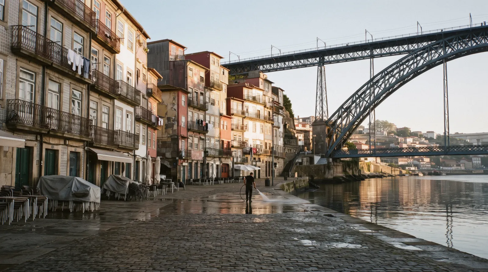 The tall painted houses of the Cais da Ribeira in Porto seen from the lower deck of the Luís I bridge at 18:40, rabelo boats moored below, Ribeira Porto