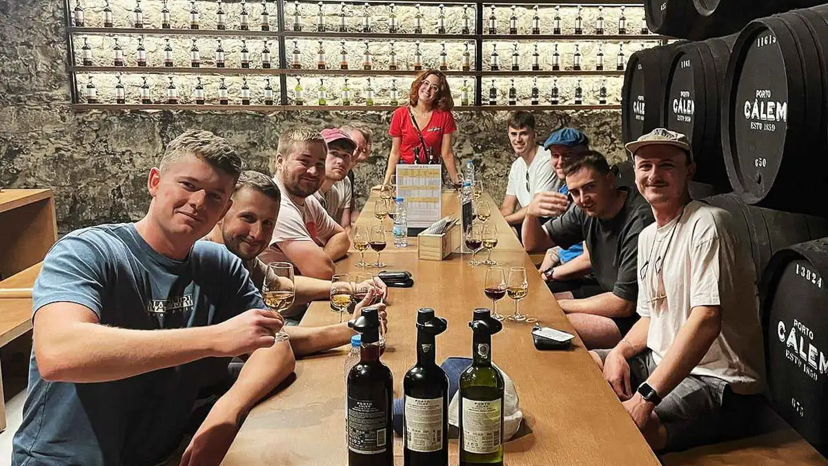 A guide leading a port tasting at a long table in a Porto wine cellar