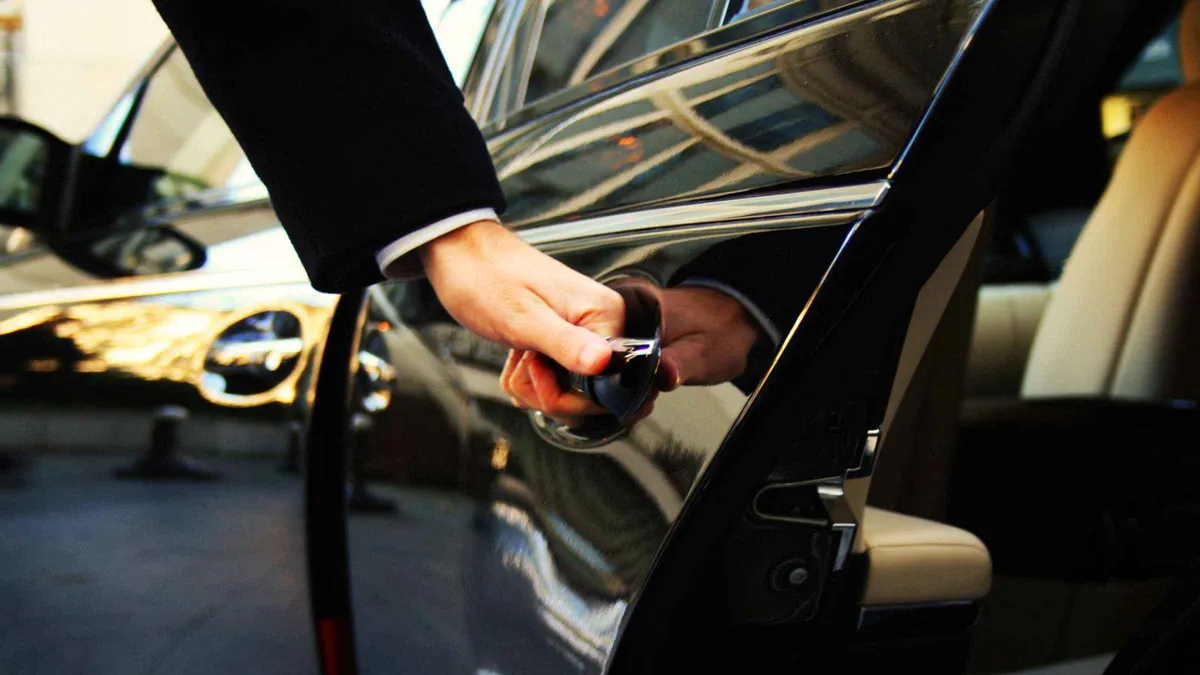 A chauffeur opening the door of a black car for a private transfer in Porto