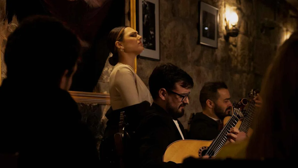Two guitarists and a singer performing fado by candlelight in a Porto tavern