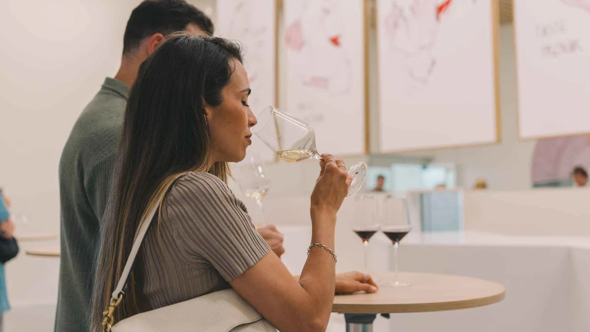 A woman tasting a glass of wine inside the WOW museum quarter in Porto